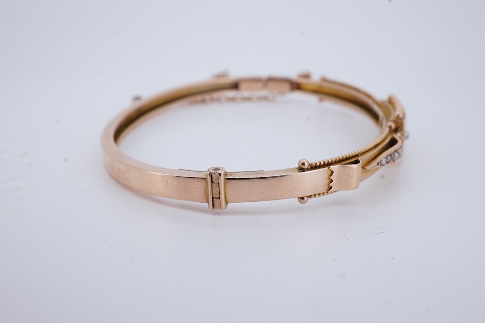 An Edwardian 9ct, seed pearl and ruby set hinged bangle, interior diameter 57mm, gross weight 8.3 grams. Condition - poor to fair